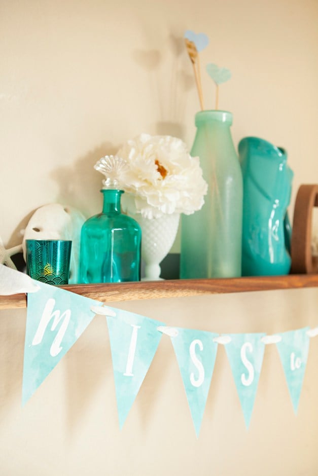 decorated shelf with teal colored bottles and a banner