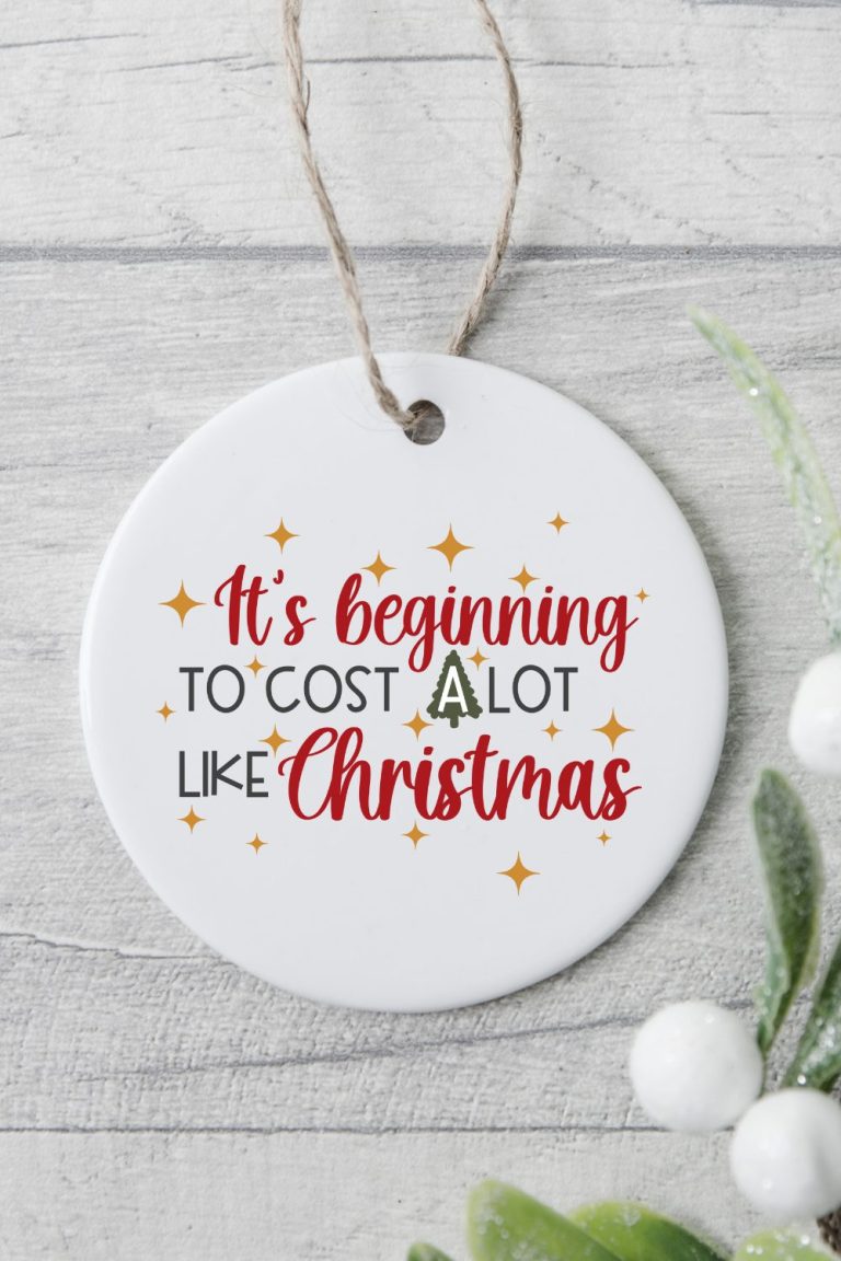 white porcelain Christmas ornament with funny christmas svg design that says it's beginning to cost a lot like christmas